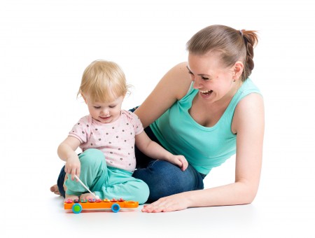 Mother And Baby Girl Having Fun With Musical Toy. Isolated On Wh